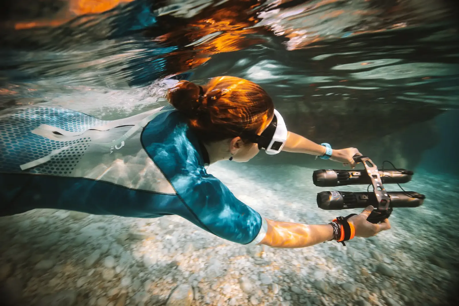 A snorkeller gliding over a pebble seabed holding the twin-engine Subnado Double sea scooter
